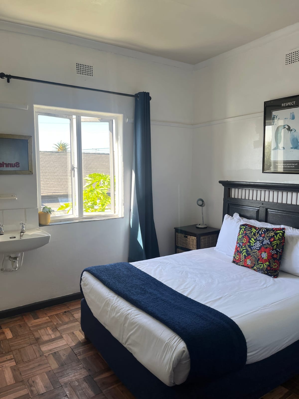 Modern hotel bedroom with black bed, white linens, blue curtains, ensuite bathroom, window with terrace view