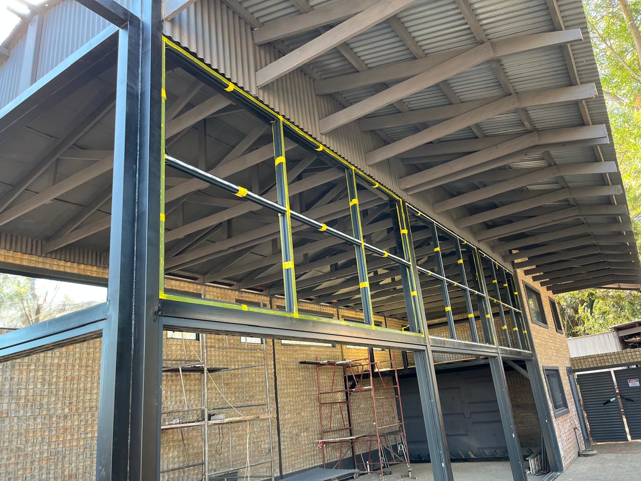 Industrial building with steel frame, metal roof, yellow and black safety railings on upper deck