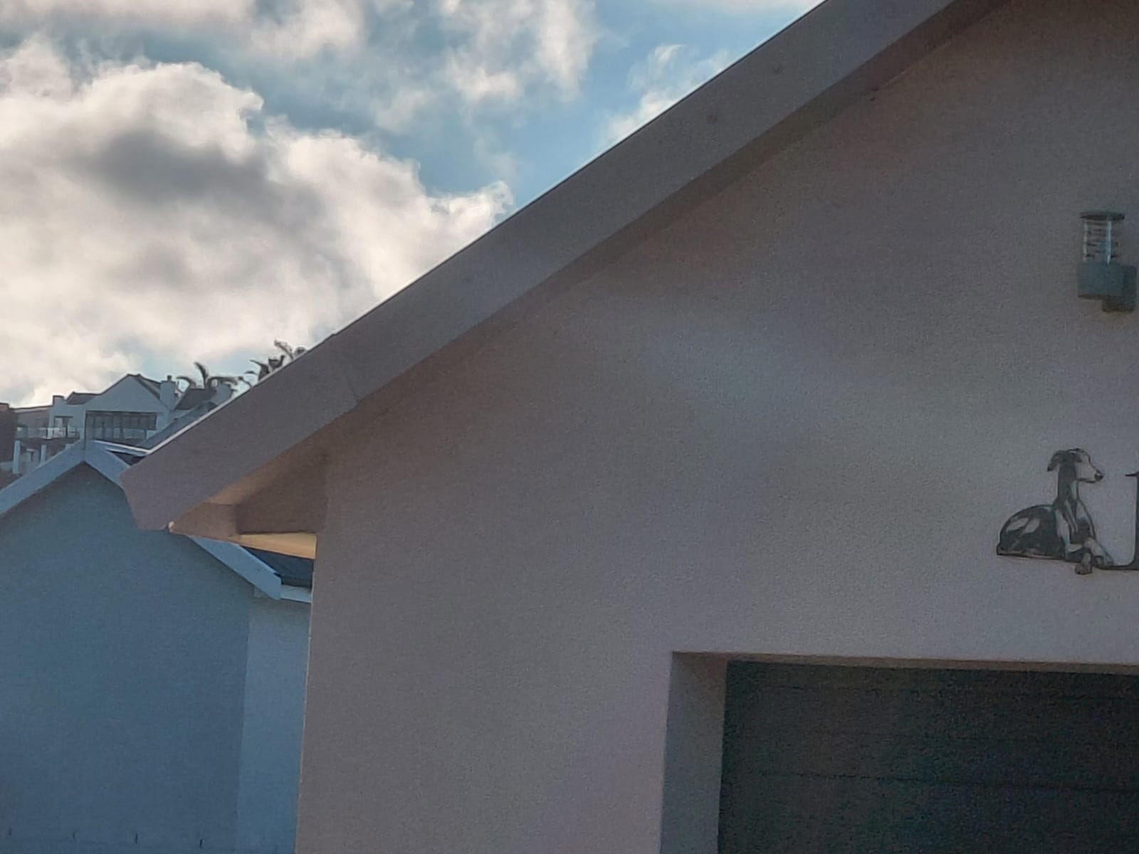 Modern white building with sloped roof against cloudy sky