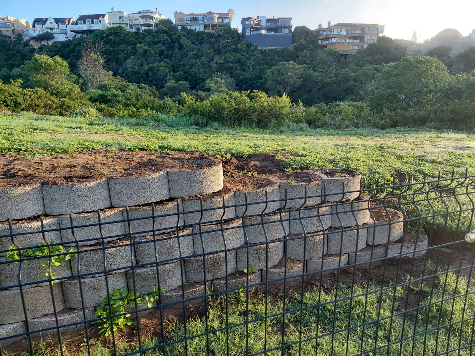 Hillside retaining walls and metal fencing overlooking valley