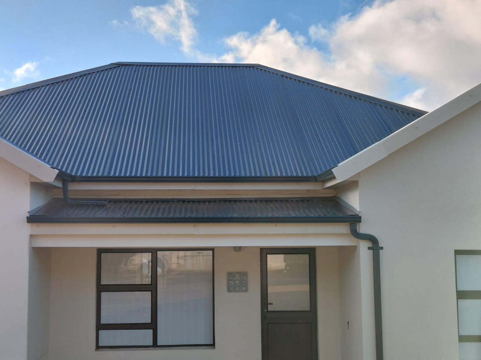 Modern white cottage with blue corrugated metal roof