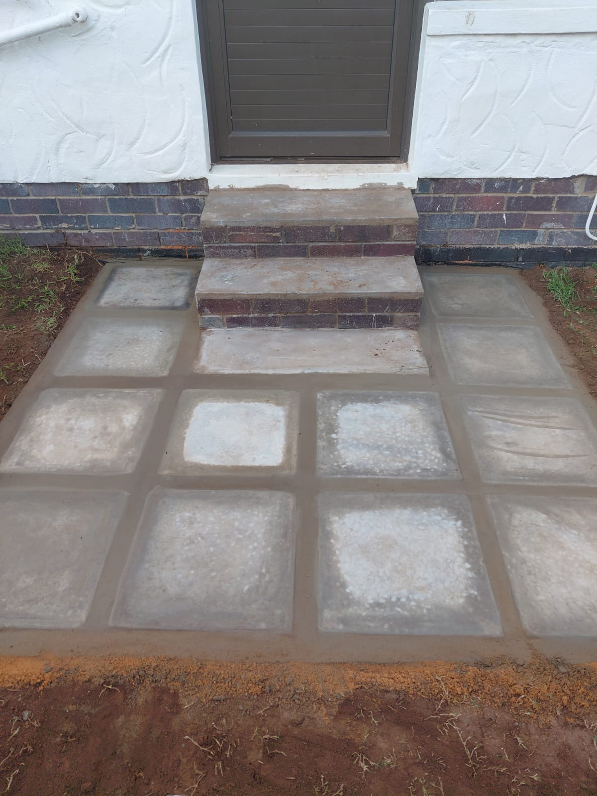 Front entrance with concrete patio and brick steps