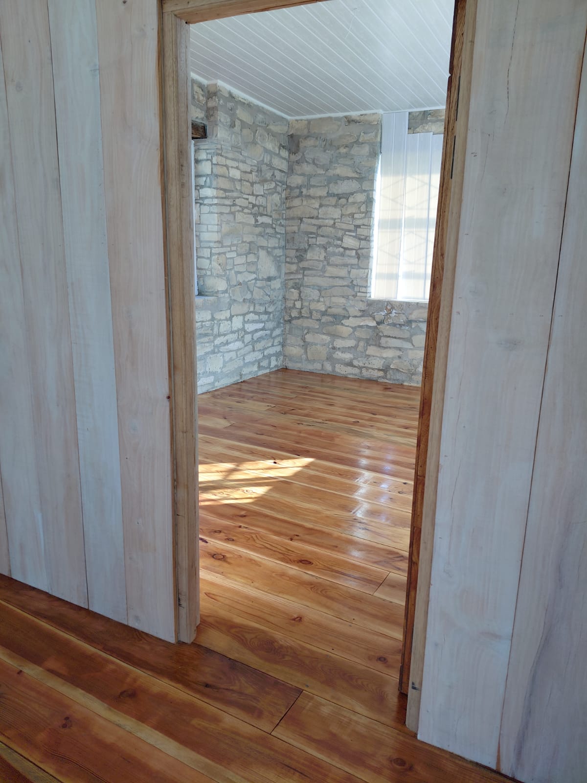 Room with hardwood flooring and exposed stone walls