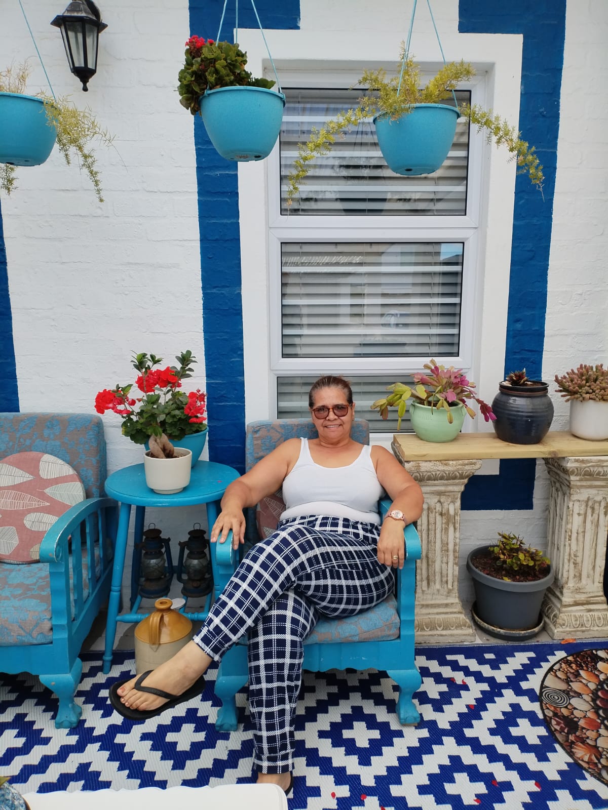 Woman sitting on a turquoise chair in a Mediterranean-style patio with blue and white accents