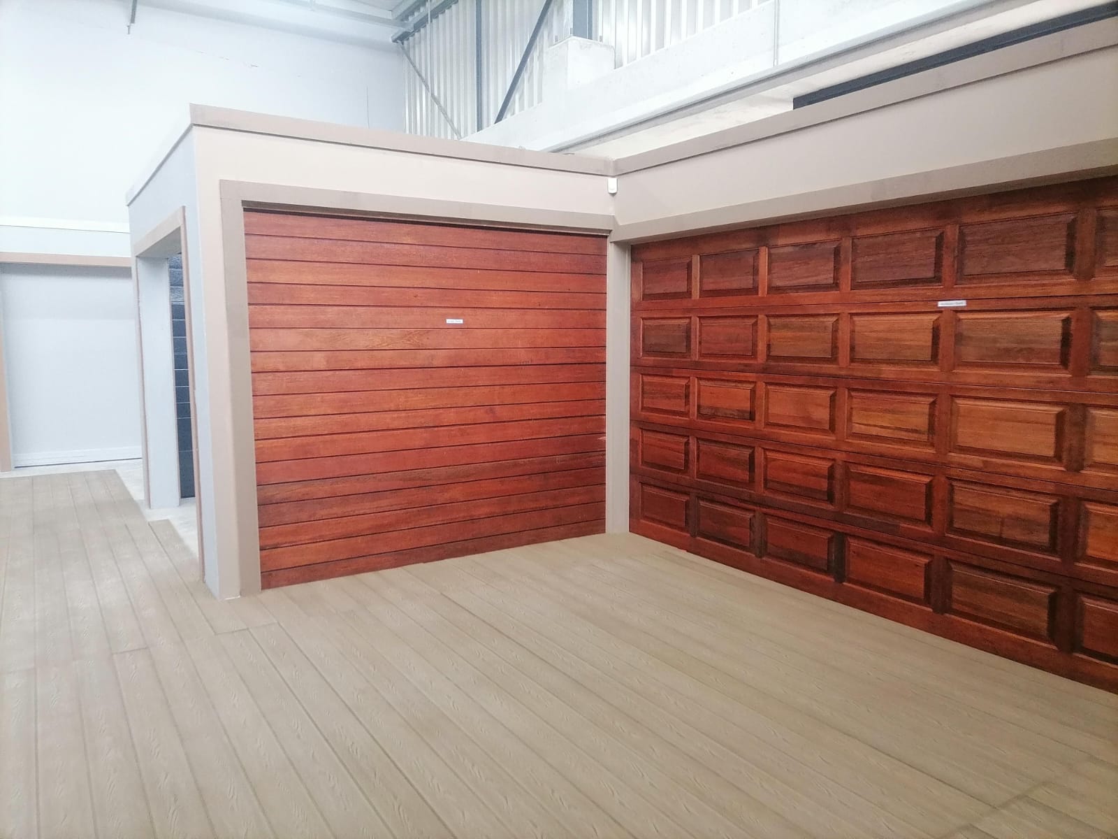 Modern garage with two red wooden garage doors and light tile flooring in a contemporary residential setting