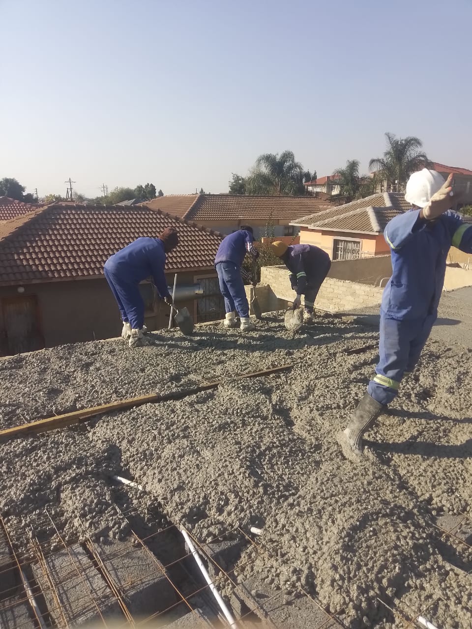 Construction workers pouring concrete on residential rooftop foundation