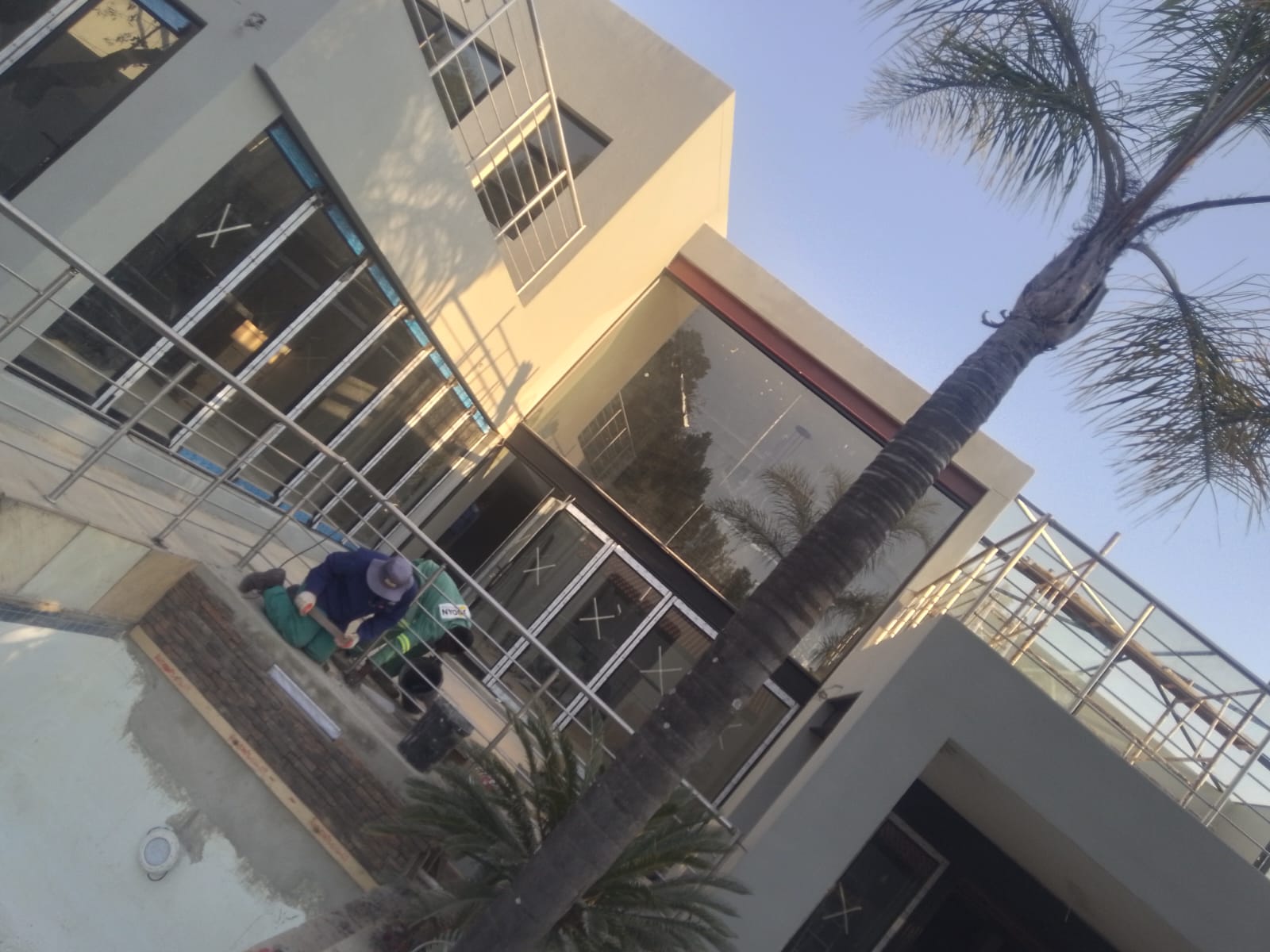 Modern multi-story white building with metal railings and palm trees