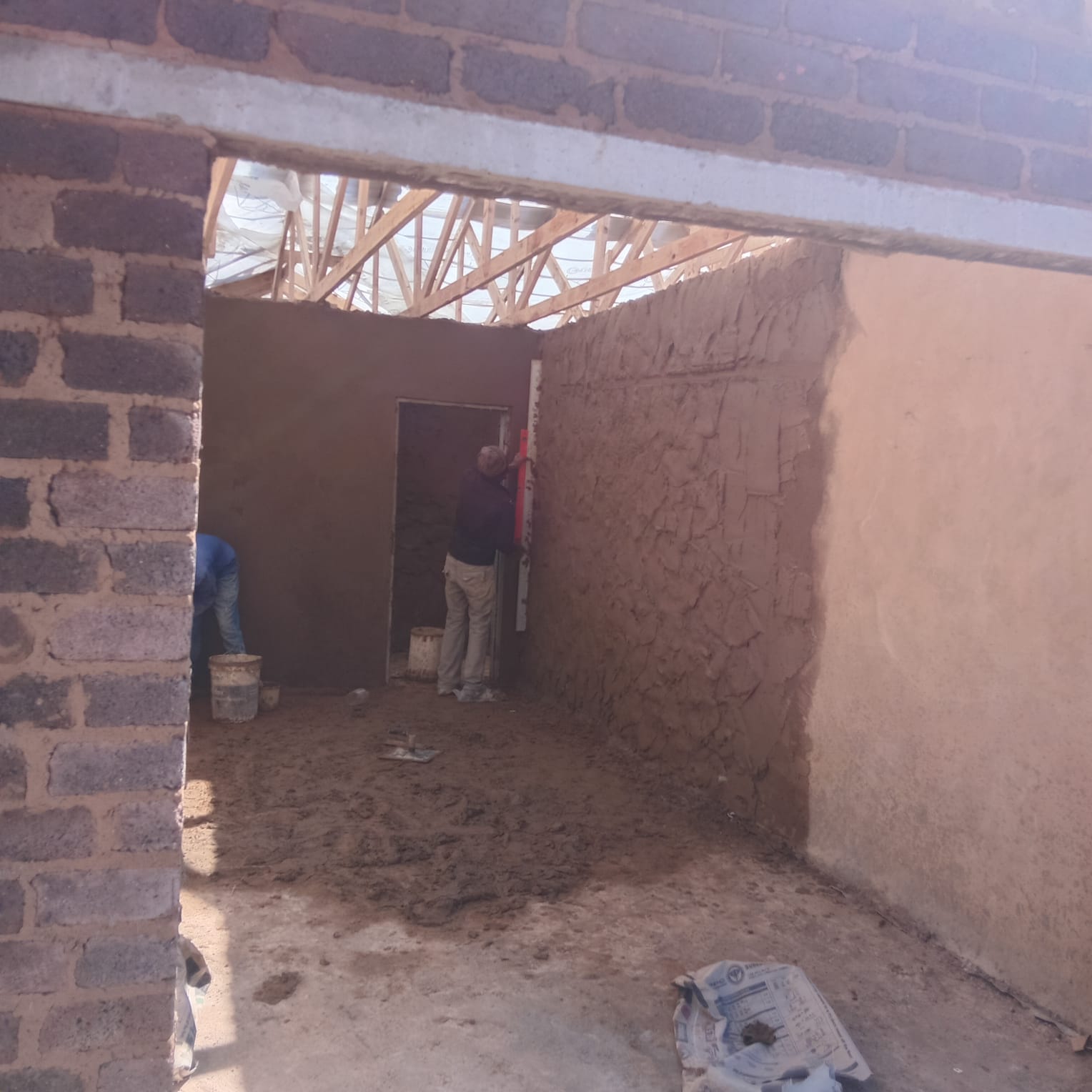 Interior construction site with brick walls and wooden roof framing