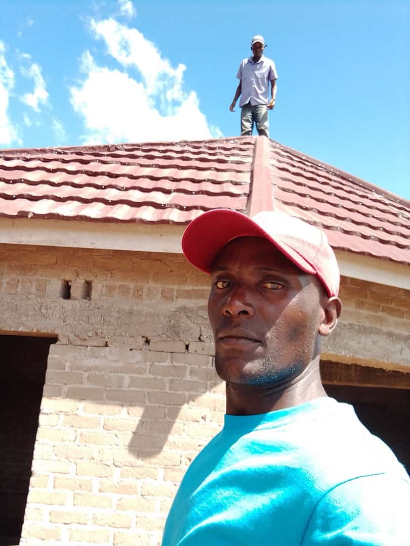 Selfie with worker on roof of brick house with red tile roofing