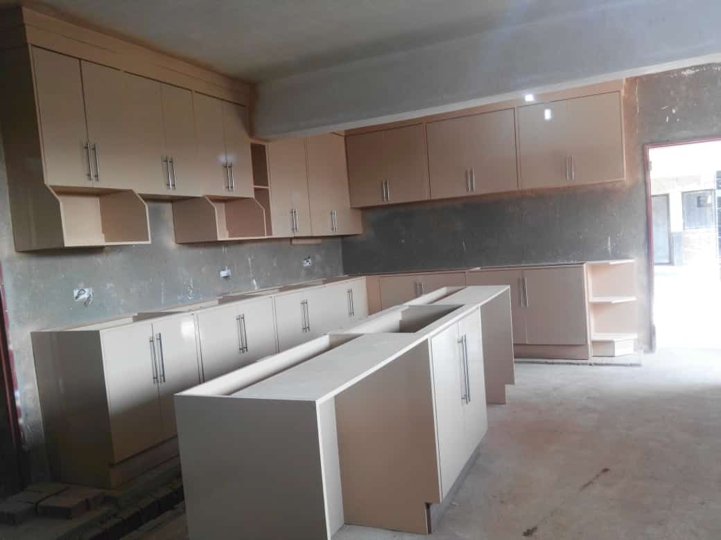 Kitchen showroom display with light wood and white cabinetry, central island, and dark backsplash