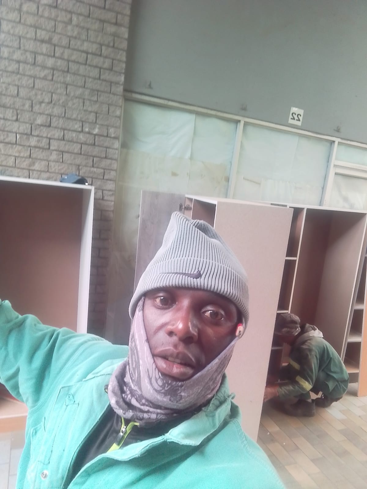 Worker selfie with shelving and brick wall in background