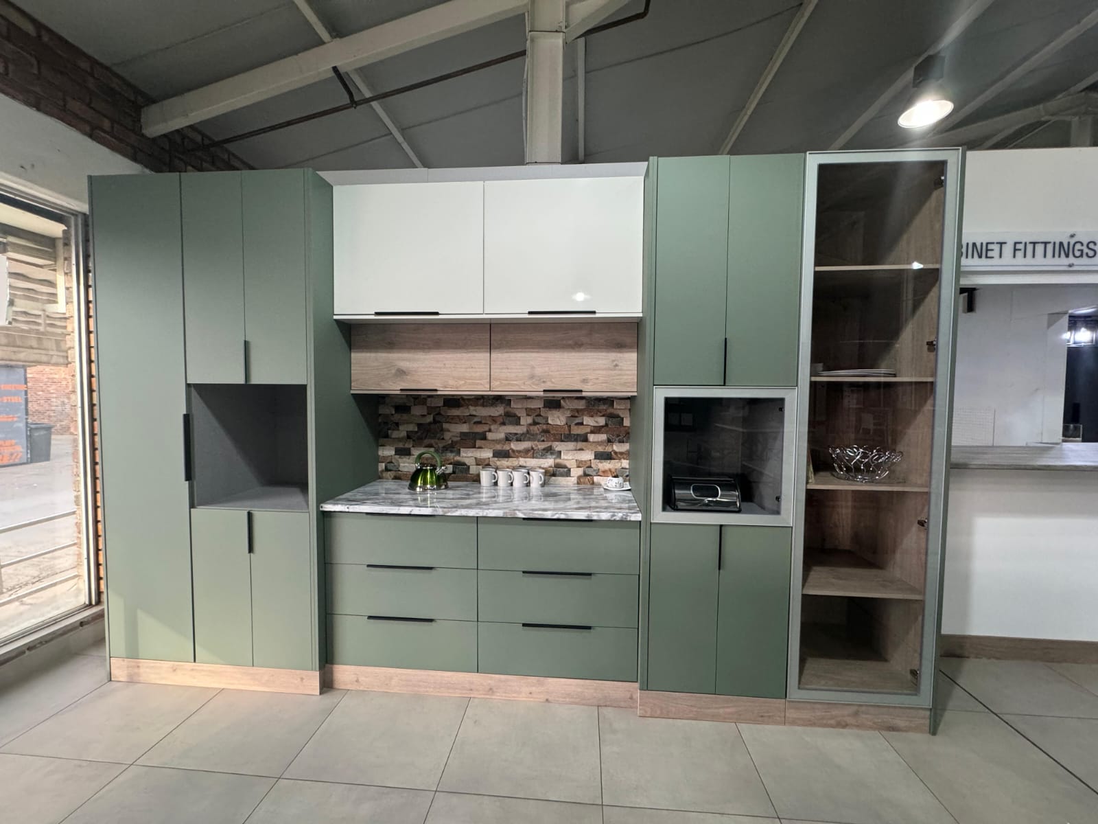 Kitchen showroom with sage green cabinets and brick backsplash