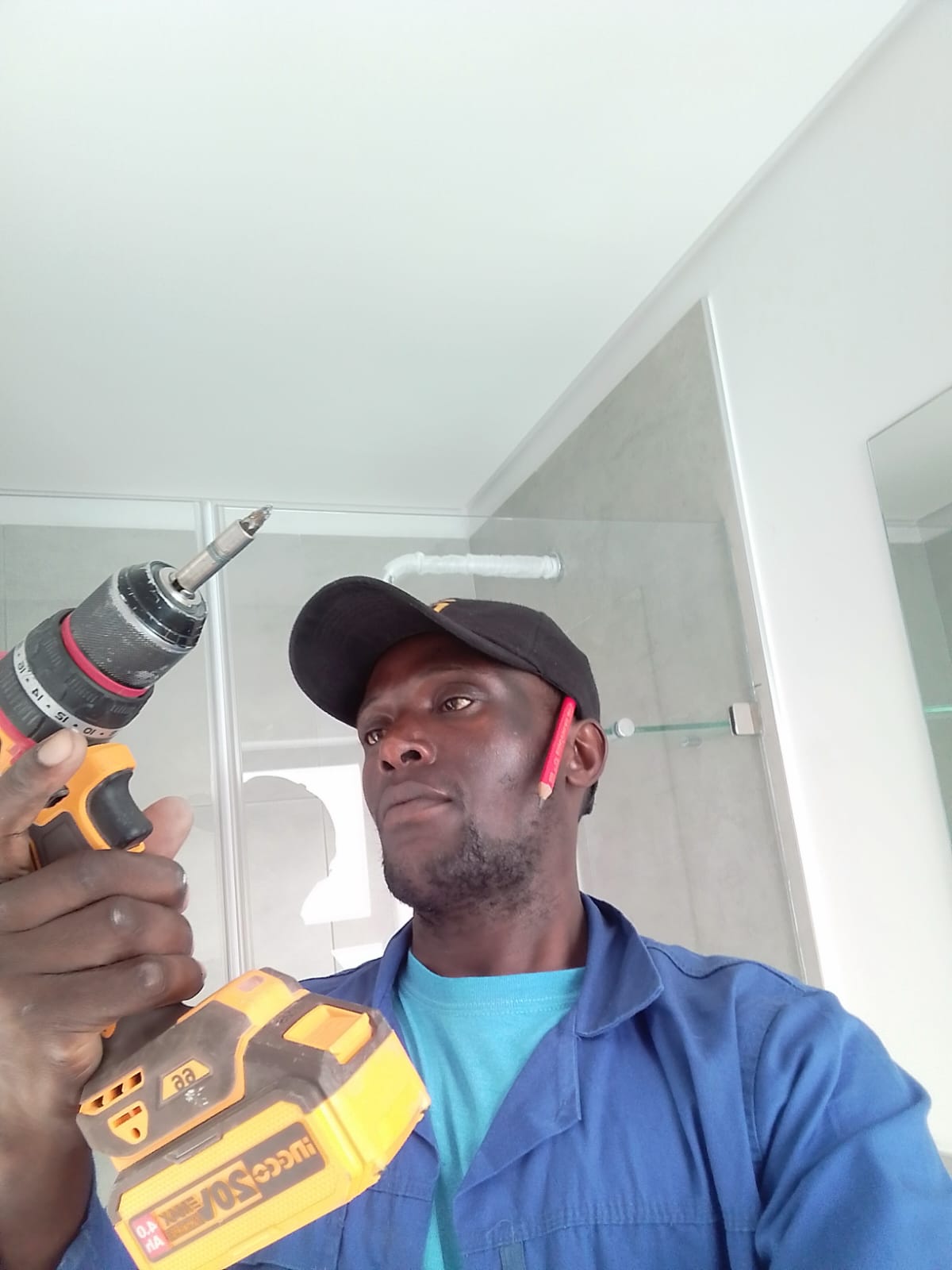 Contractor in blue work shirt holding power drill in front of interior wall