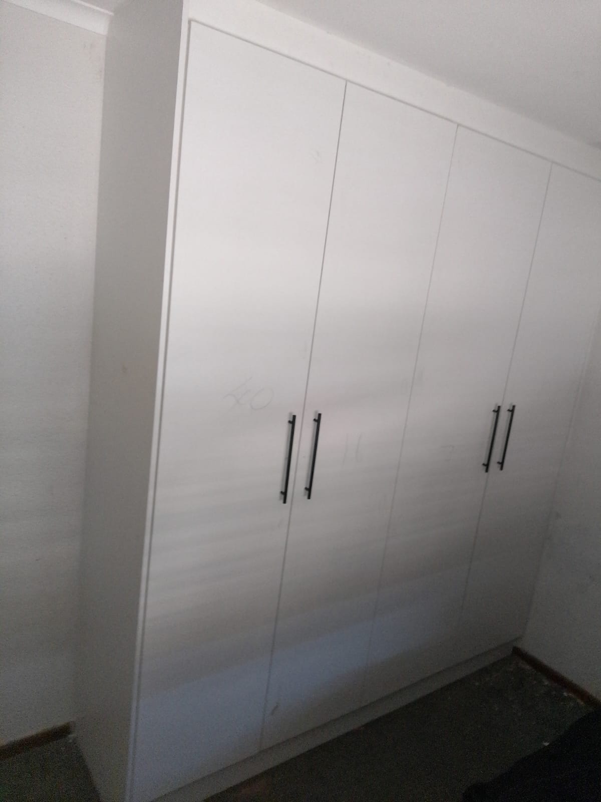 Modern white built-in wardrobe with black handles in bedroom