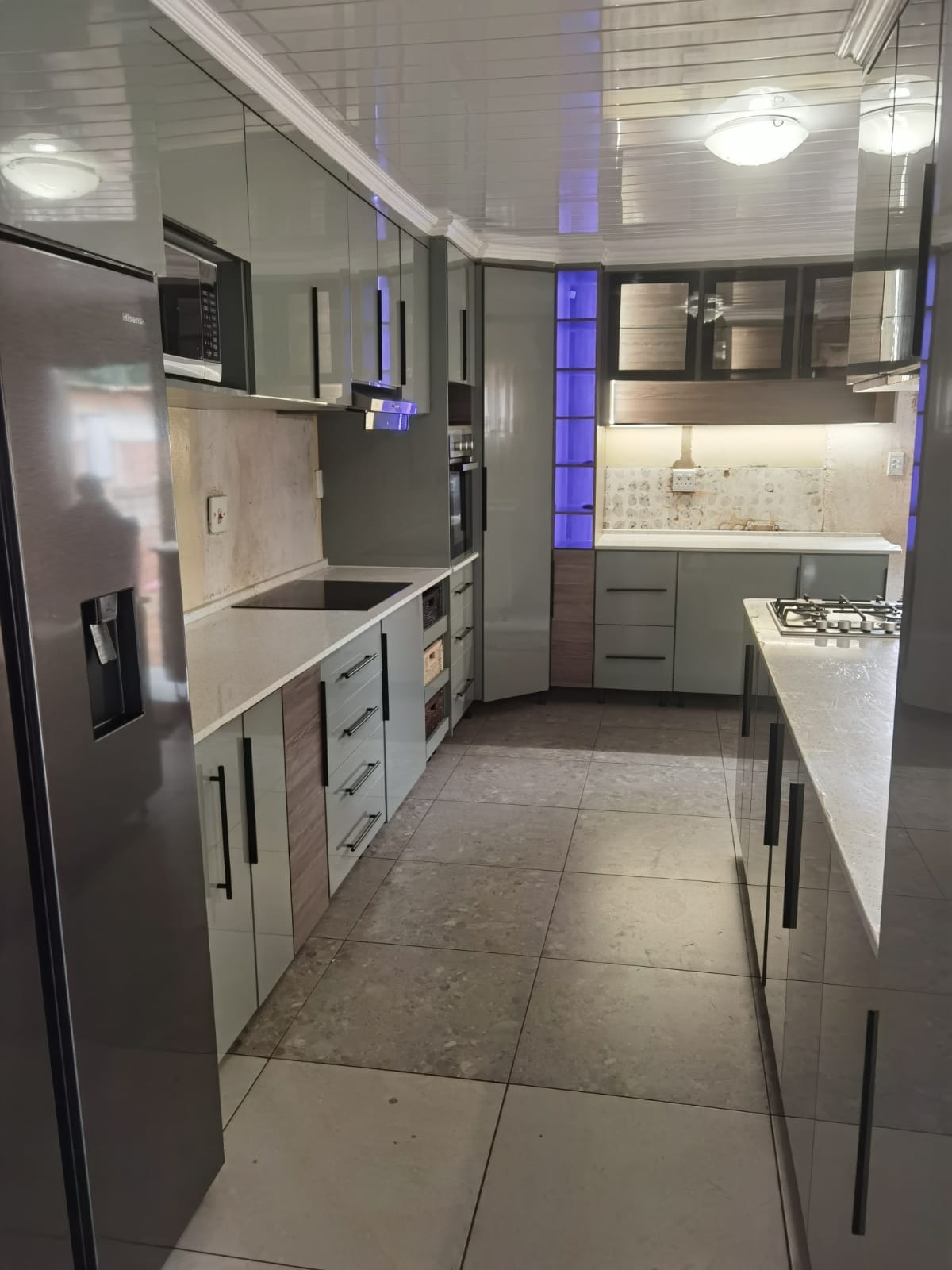 Kitchen showroom display with white cabinetry, wood accents, and blue lighting