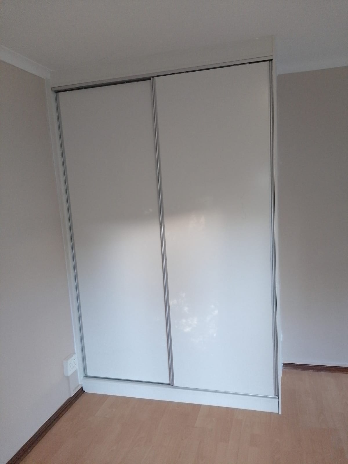 Bedroom with large sliding wardrobe with mirrored doors and silver frame