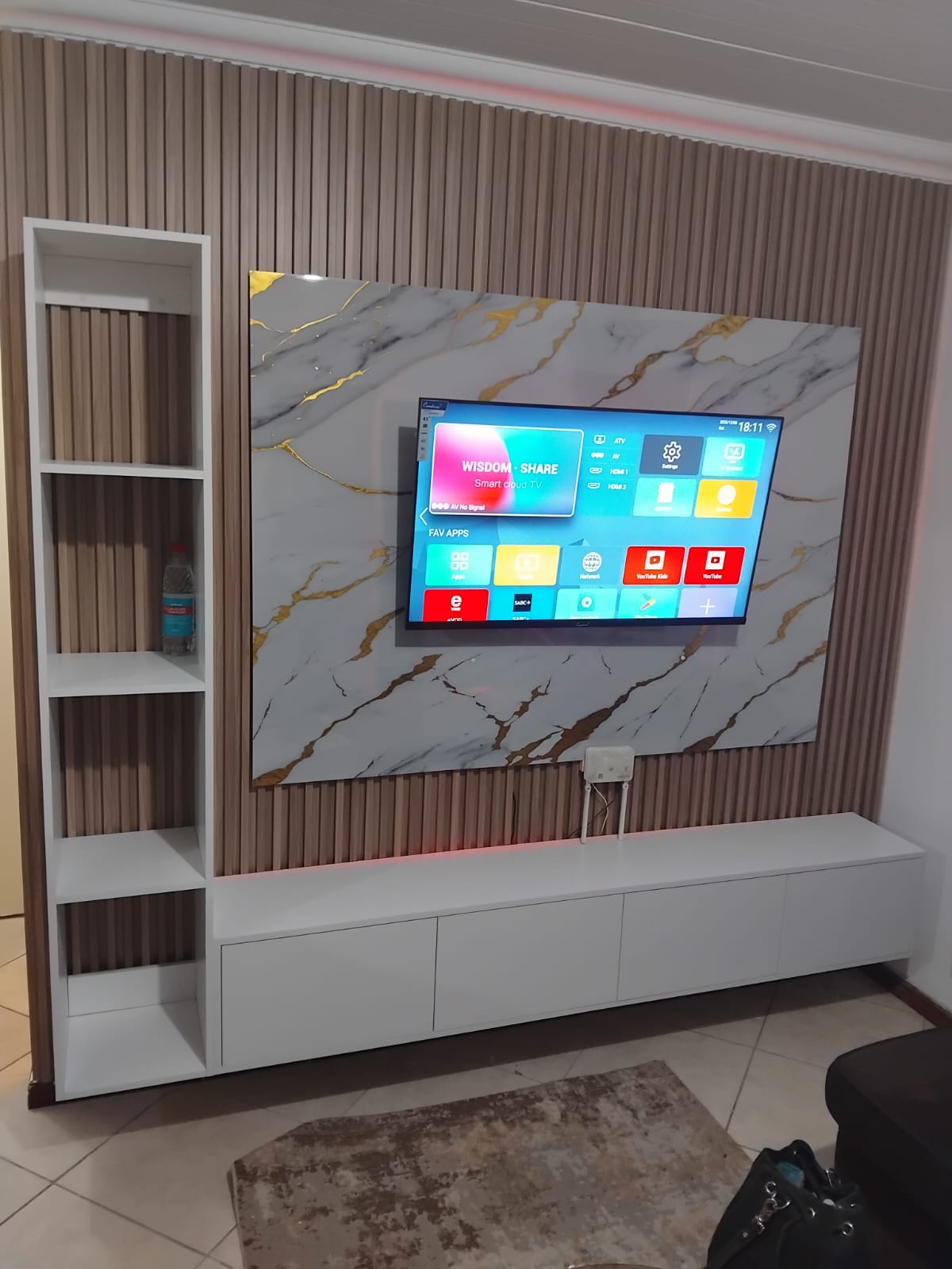 Modern living room with wall-mounted TV and white shelving unit showcasing carpentry work