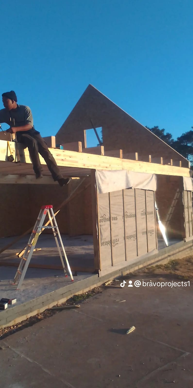 Worker sitting on house framing