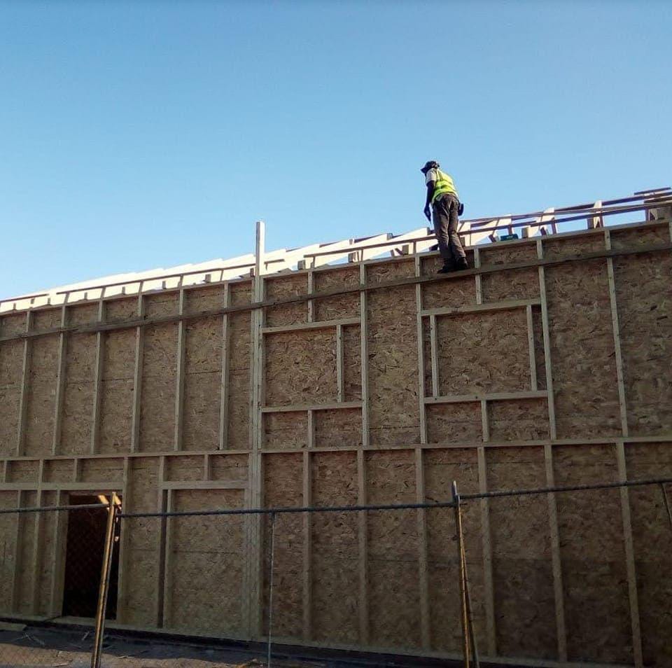 Worker on wooden frame under blue sky