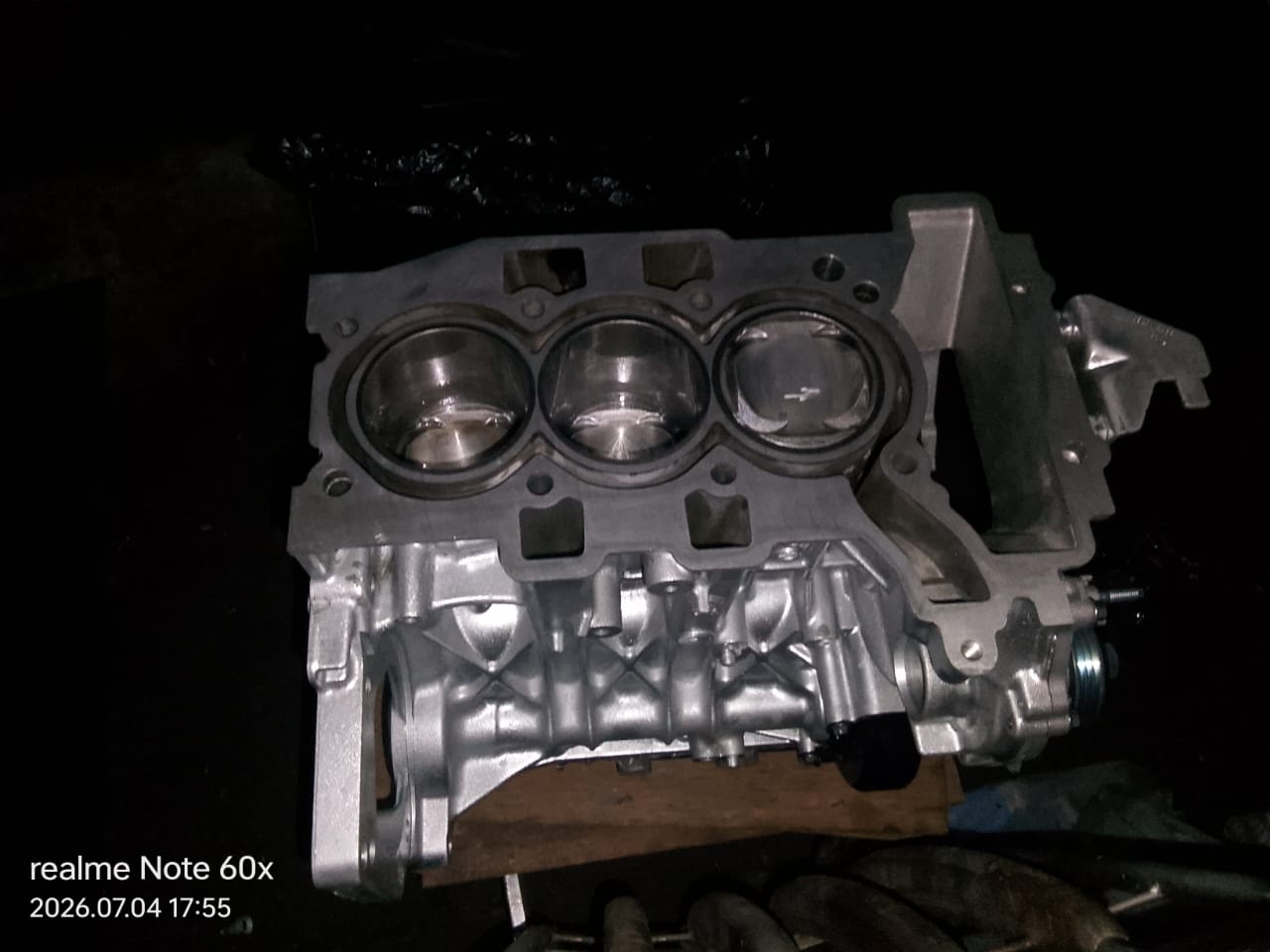 Three-cylinder engine block with pistons visible through the cylinder head