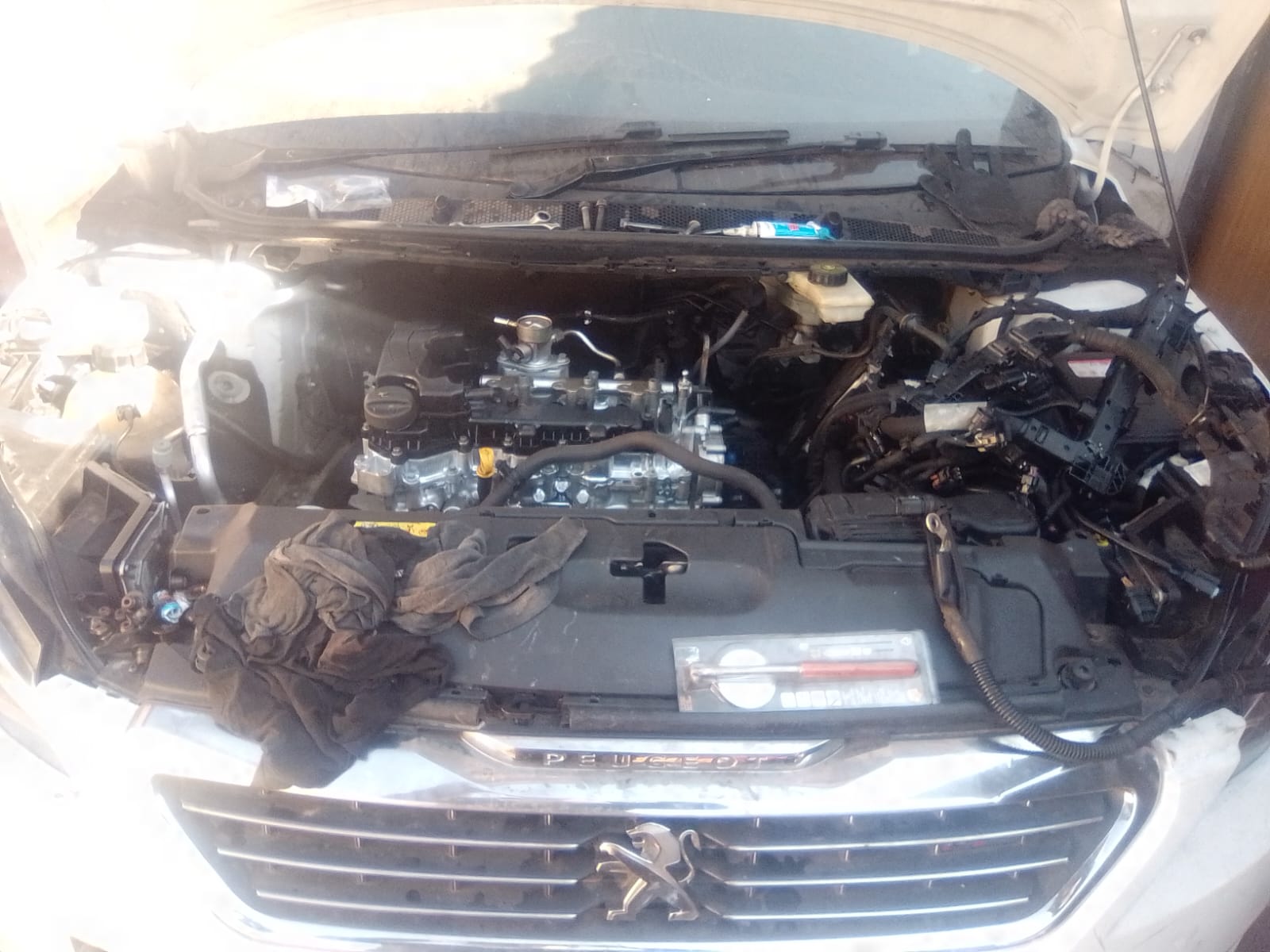 Open engine bay of a Peugeot vehicle with hood propped up revealing engine components