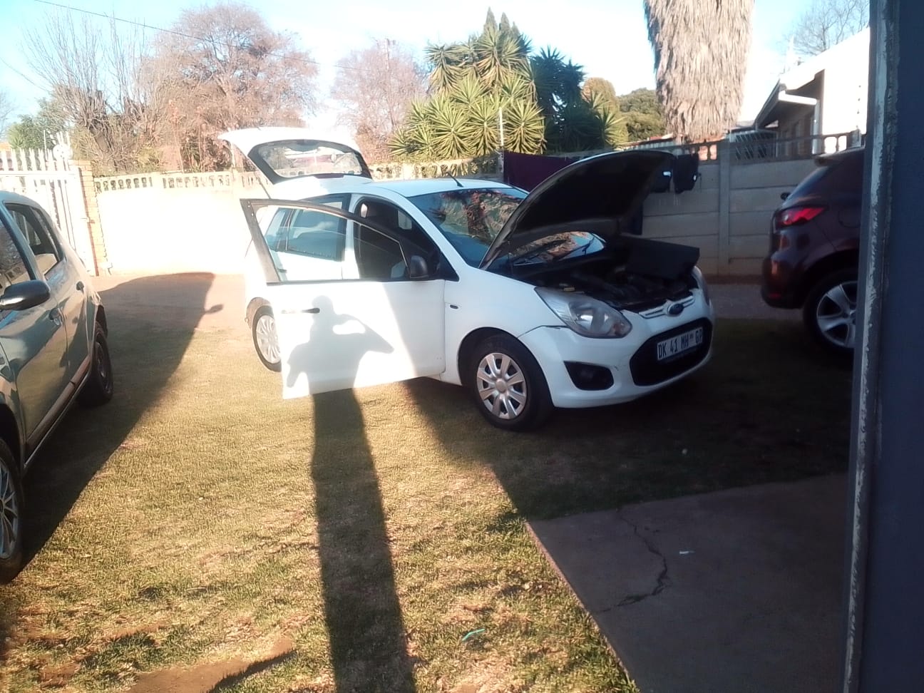 White compact car with hood and door open during mobile mechanic on-site repair