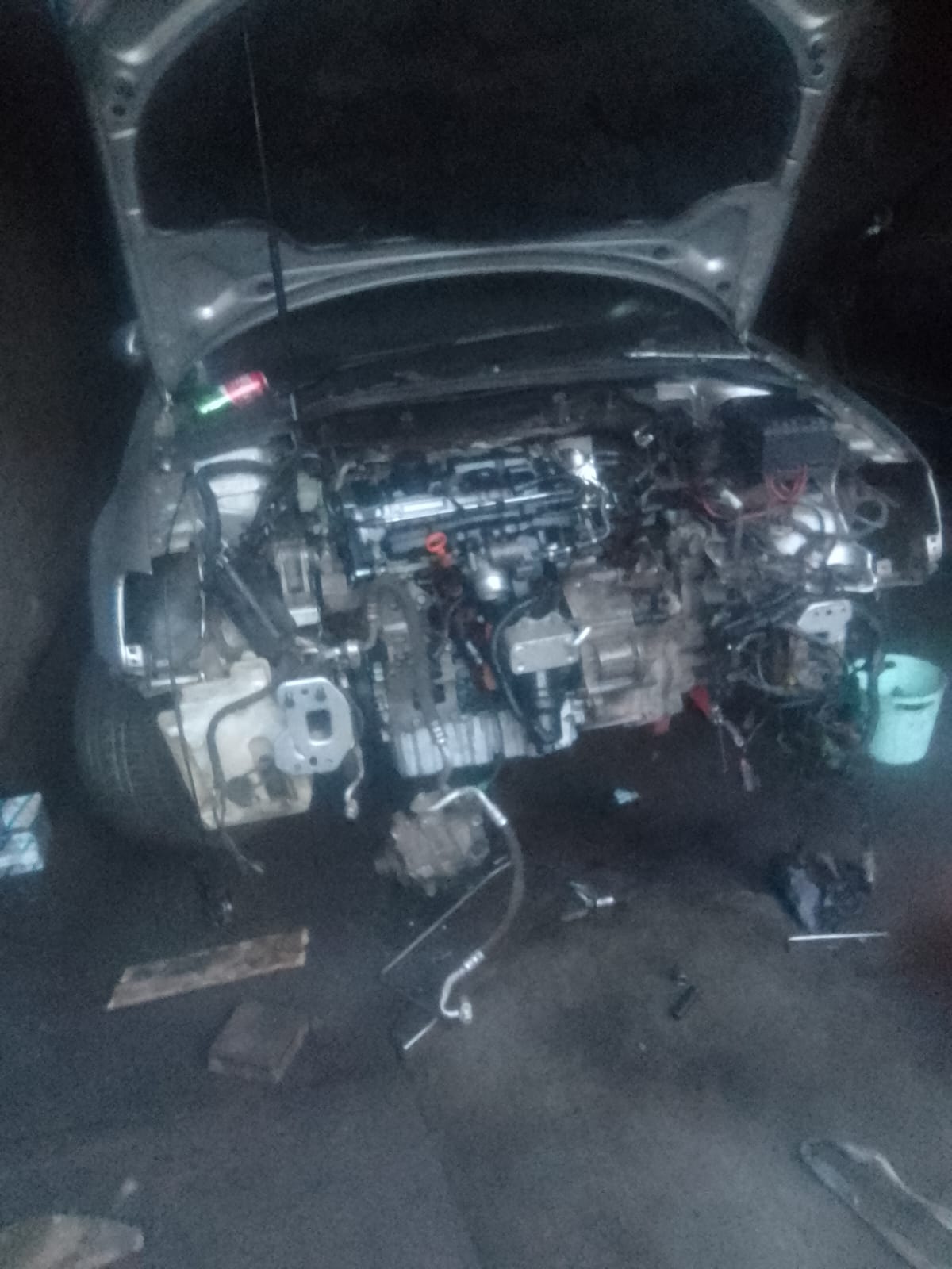 Open car hood revealing engine compartment under night lighting