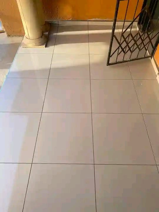 Room with light beige ceramic tile flooring, a yellow column, and a black metal gate