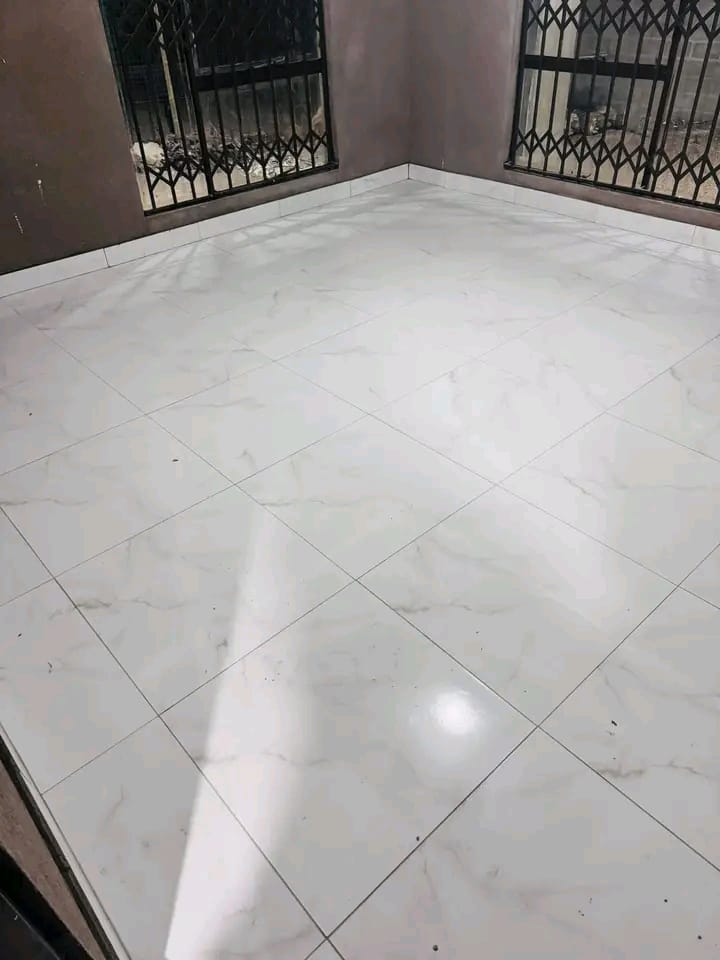 Room with marble-effect floor tiles, gray walls, and two black security gates