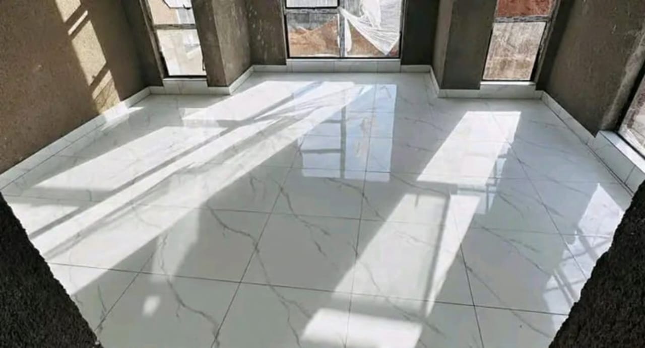 Empty room with polished white marble tile flooring and sunlight casting shadows