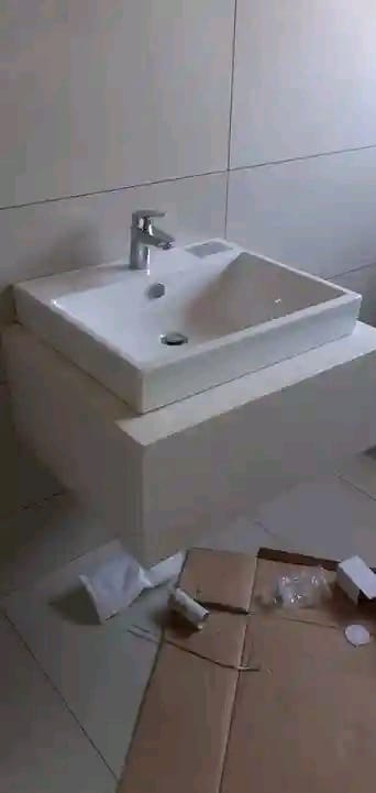 Modern white square bathroom sink with chrome faucet against tiled walls