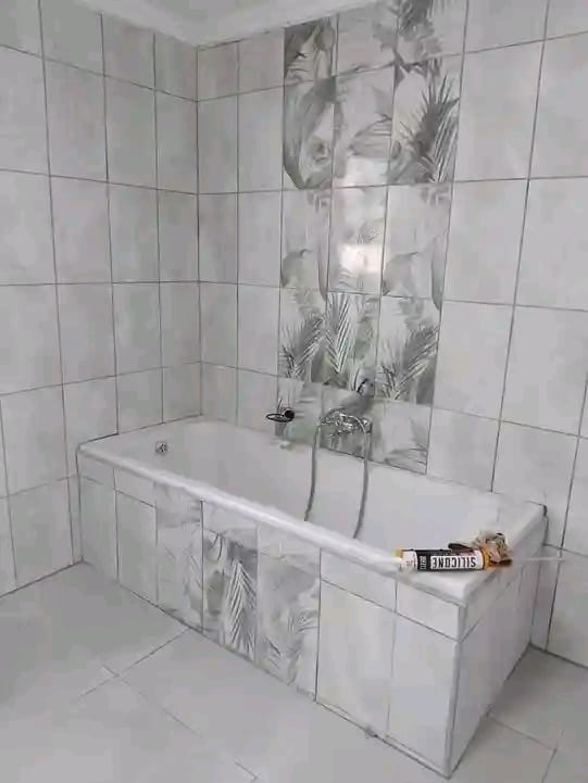 Modern bathroom with white tiled bathtub and tropical palm leaf glass shower