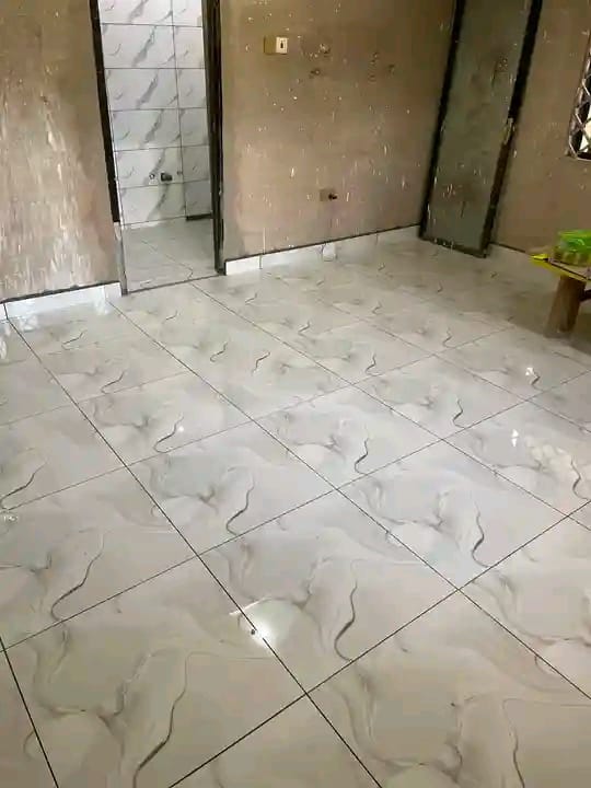 Empty room with marble-patterned floor tiles and construction materials in the background