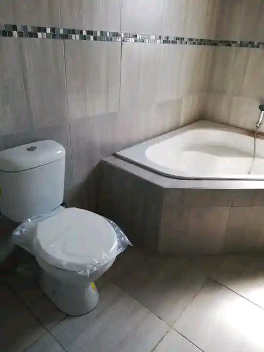 Bathroom with white toilet and corner bathtub with tiled walls