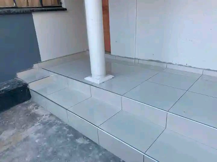 Large light gray tile flooring in a utility room with white walls