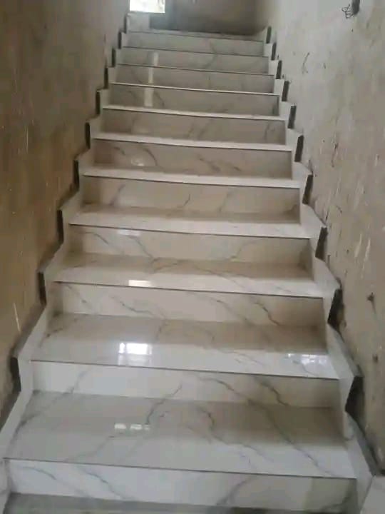 White marble-effect tiled stairs with metal handrails on both sides