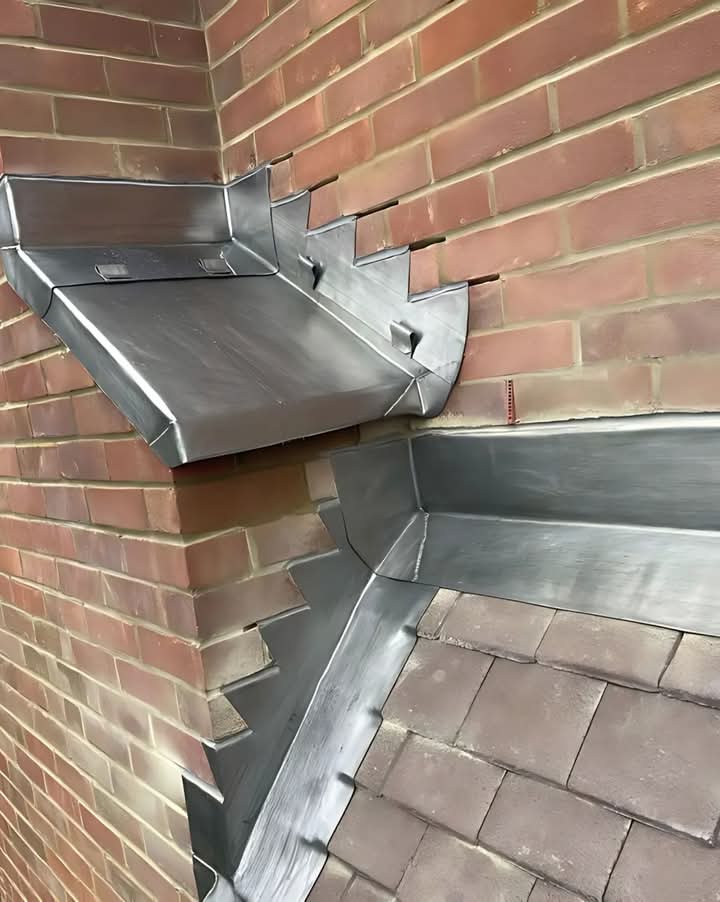 Metal guttering and downspout installation on brick building