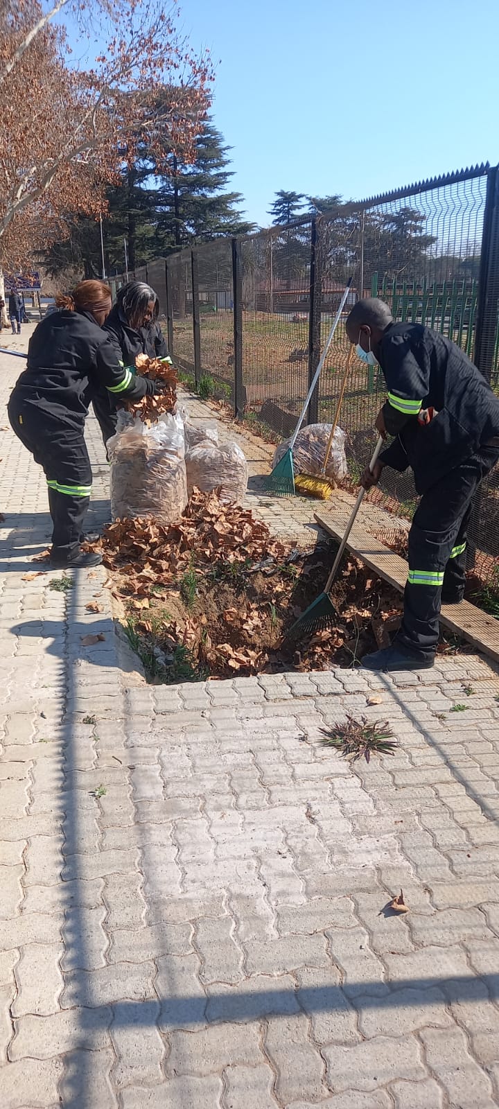 Workers cleaning paved area near sports court