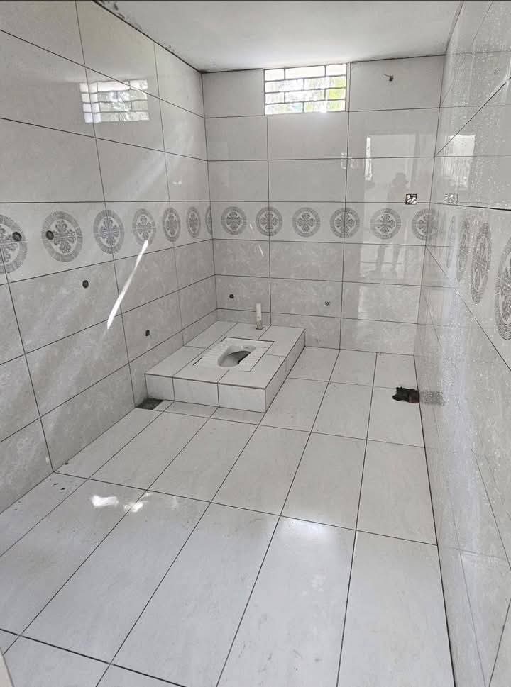 Bathroom under construction with gray tiles and squat toilet