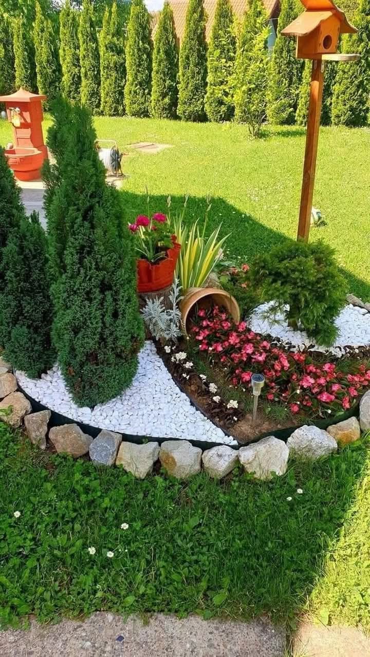 Landscaped garden bed with pink and white flowers and birdhouse