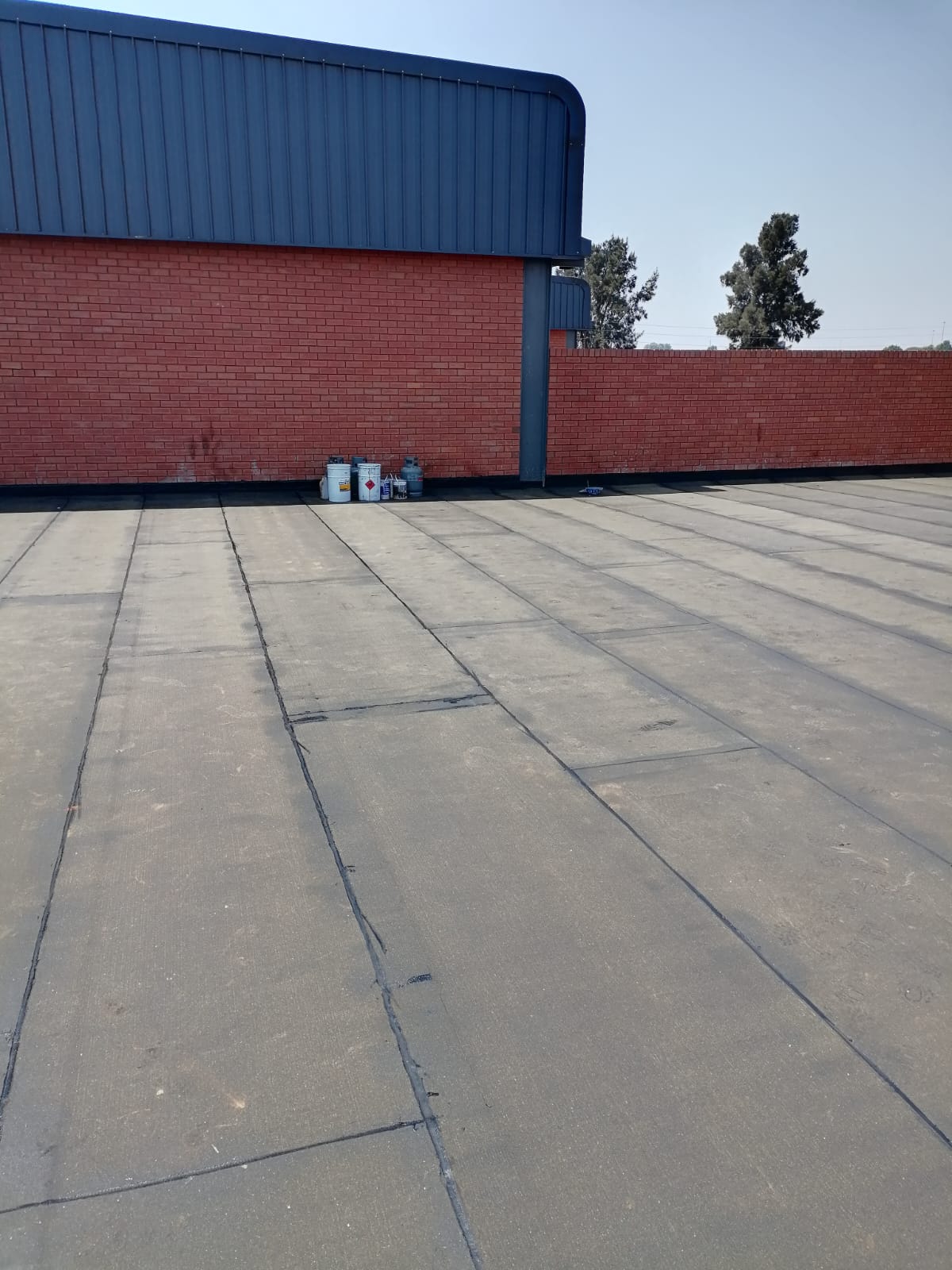 Industrial building with red brick wall and blue metal roof