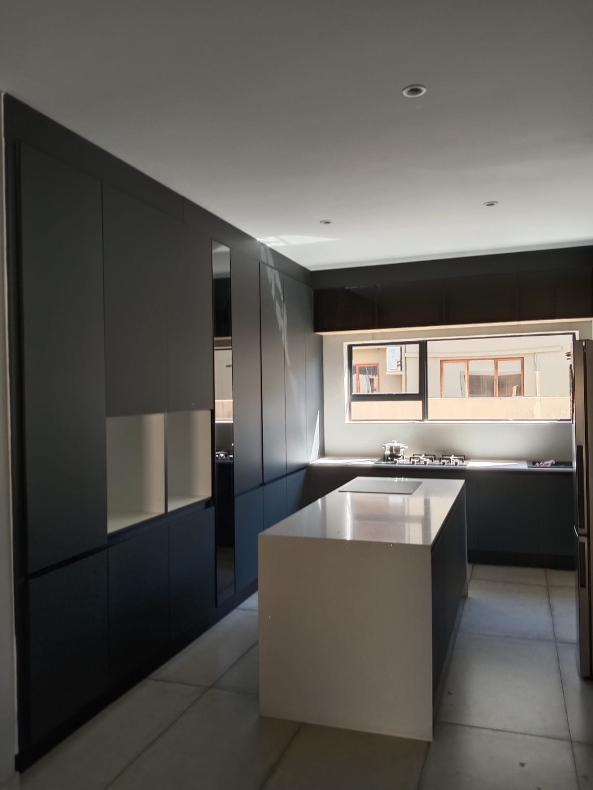 Modern kitchen with black cabinetry and white central island designed by Kubaz Cabinetry