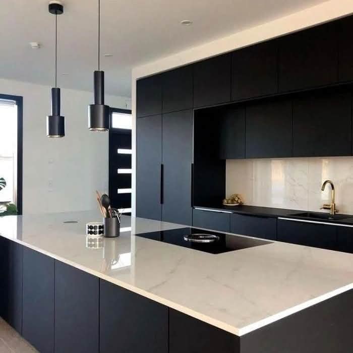 Luxury kitchen with black cabinetry, white marble countertop and pendant lights