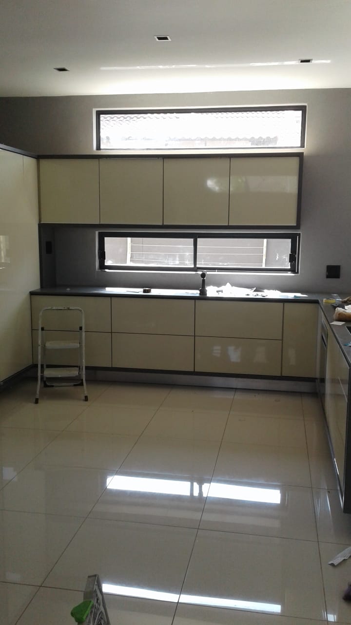 Kitchen cabinetry installation in progress showing cream-coloured units and dark countertop