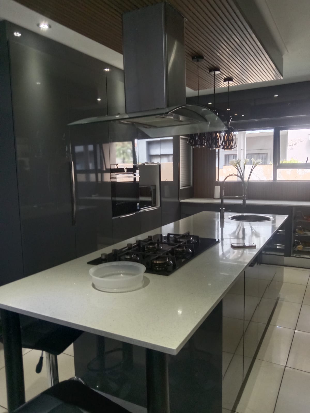 Modern kitchen with dark cabinetry, white island and pendant lighting