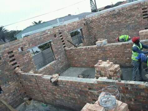 Worker in safety gear inside a brick building foundation under construction