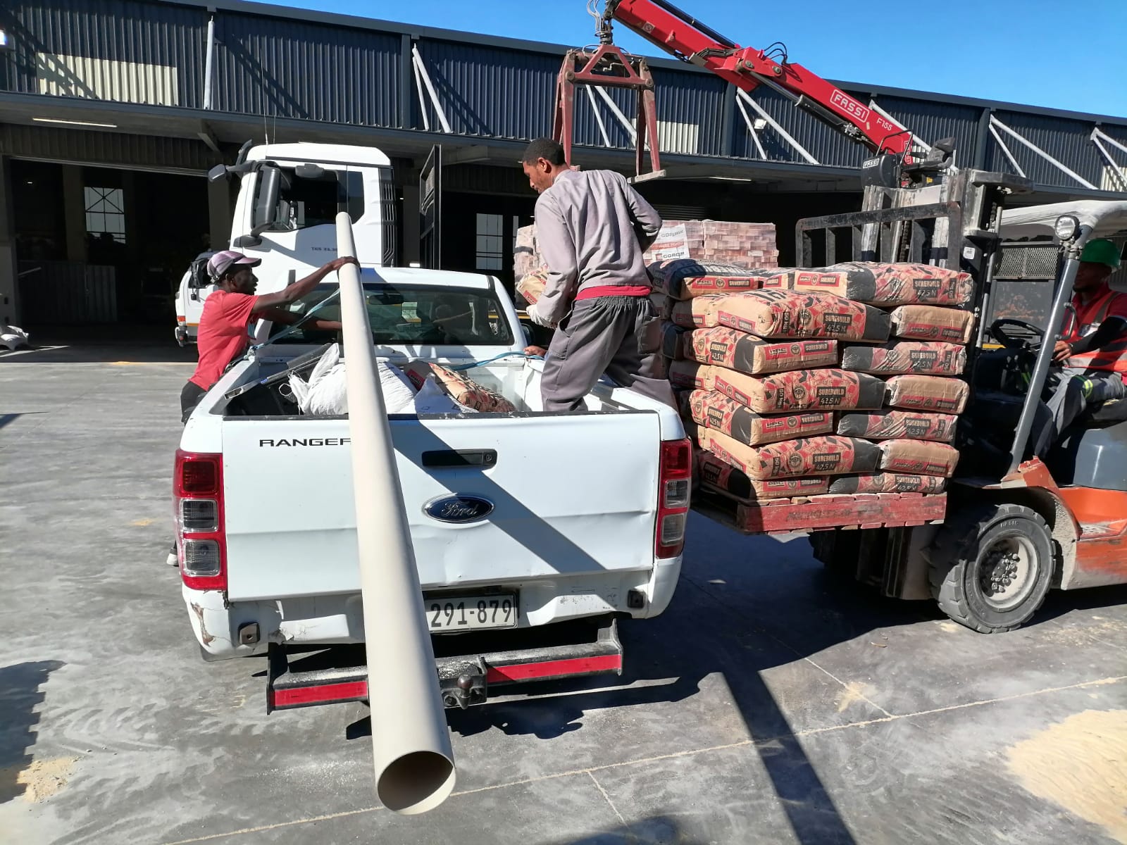 Team loading building materials onto a pickup truck at a warehouse