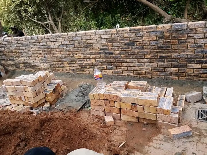 Stacks of terracotta bricks in front of a newly built brick wall