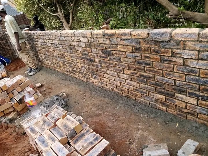 Newly constructed brick retaining wall with construction materials on site