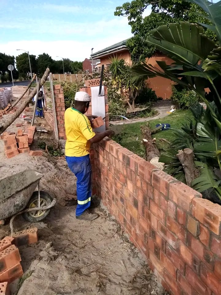 Construction worker in hard hat building a brick wall at a residential property